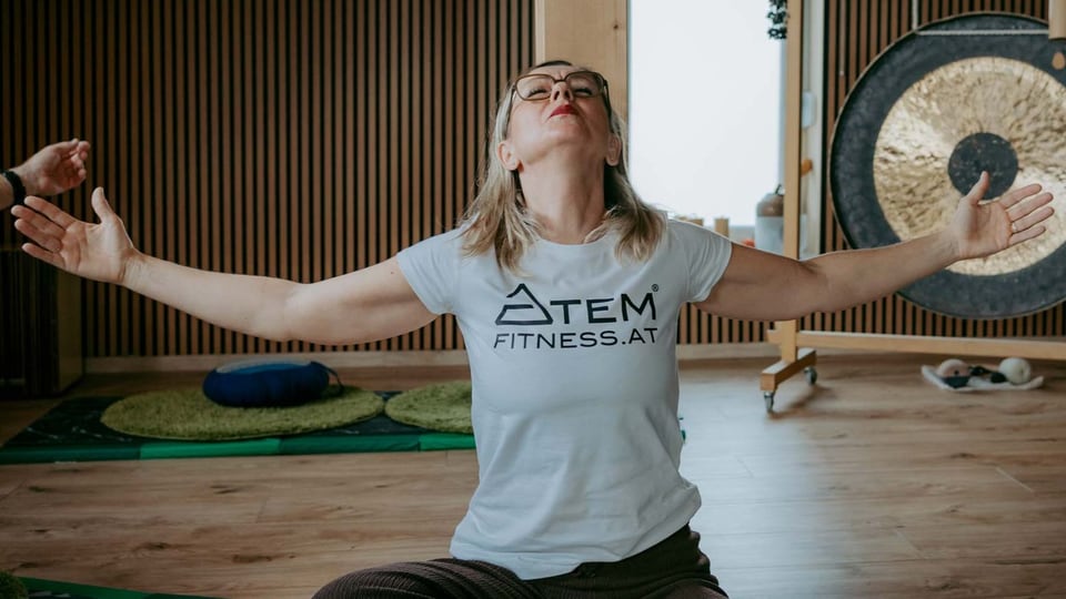 Teilnehmerin öffnet während einer Atemübung die Arme