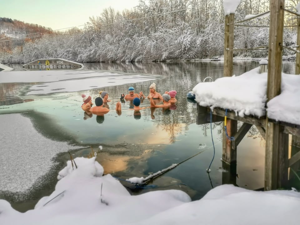 Gruppe badet im Winter gemeinsam in einem verschneiten See