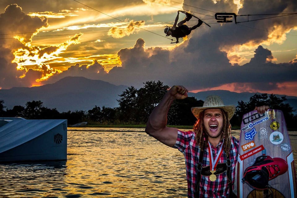 Daniel Fetzy Fetz jubelt mit Weltmeistermedaille und Wakeboard vor einem Sprung im Sonnenuntergang