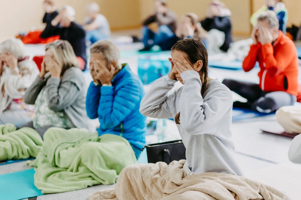 Teilnehmende bedecken während einer angeleiteten Übung ihre Augen